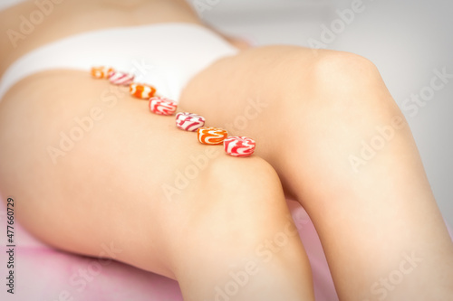 Round candies lying in a row on the female leg with copy space, depilation concept