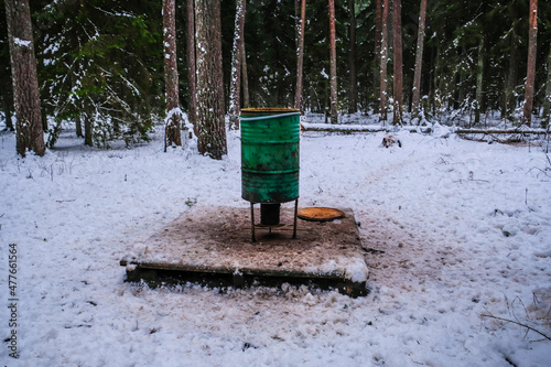 Manger for winter feeding of wild animals in forest. Forest animal feeder in winter. Defocused photo