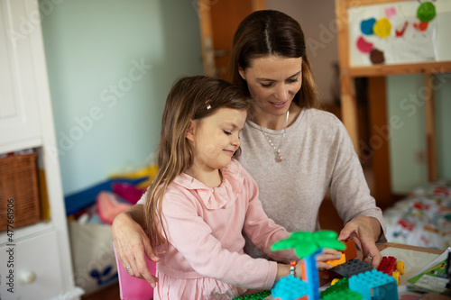 Adorable girl playing with toys at home. Little child playing with mother.