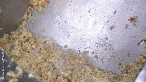 Men 's hands are raking out crushed apple paste for cider production mushed by machine from a stainless steel tank. Fruit vitamin paste. Raw vegan vegetarian healthy food concept 4k