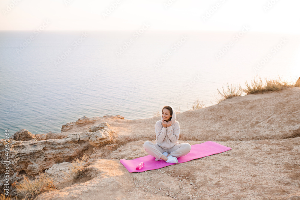 Young beautiful woman doing yoga pose wear sport suit practice over nature sea background. Healthy lifestyle. Girl work out outdoors.