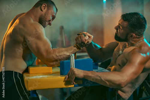 The Armwrestling. Two strong athletes in the gym compete in arm wrestling. Bodybuilders armwreslers in athletic training room