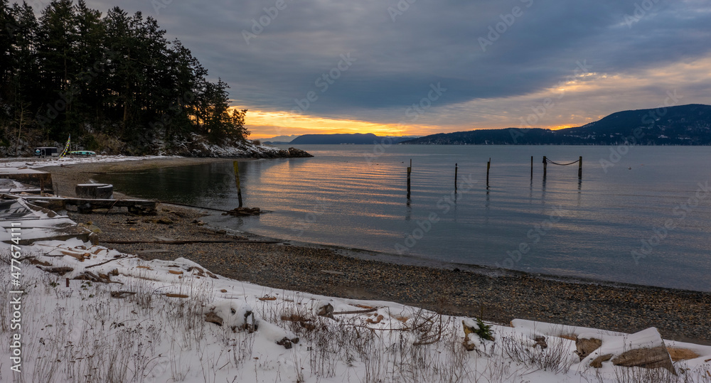 Snowfall in the San Juan Islands of the Pacific Northwest. A somewhat rare snow event blankets the beaches and mountains during a wintry sunset of western Washington state.