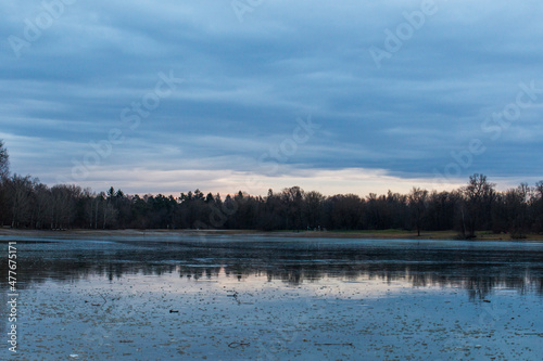 Sunset over ice sheet on Kuhsee lake in recreation area near Augsburg