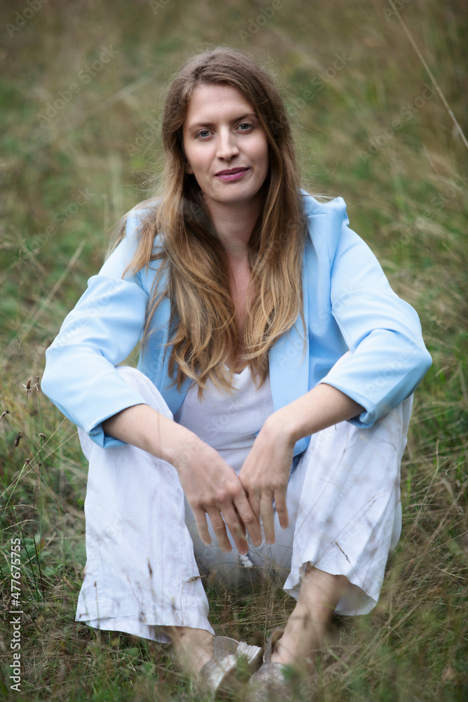 portrait of blond woman sitting outdoors in the grass portrait of blond woman sitting outdoors in the grass