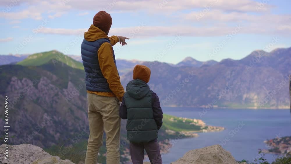 A father and son travel in Montenegro in autumn. They look at the Boka Kotorska bay from a view point on a mountain