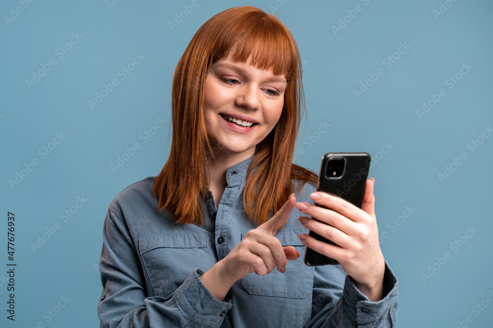 Cheerful woman using cellphone and smiling, reading good news message, enjoying mobile application Cheerful woman using cellphone and smiling, reading good news message, enjoying mobile application