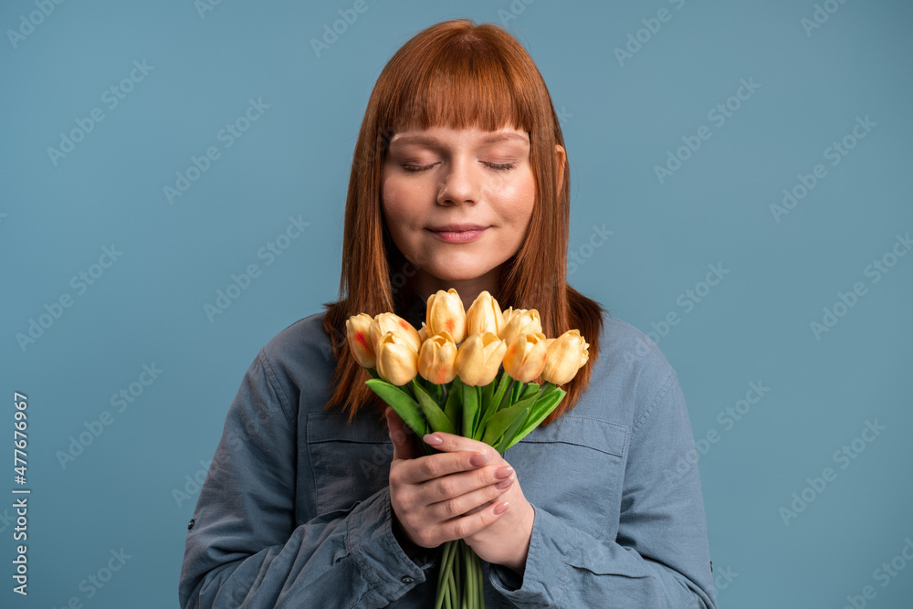 Portrait of romantic beautiful ginger girl smelling flowers bouquet and smiling with pleasure Portrait of romantic beautiful ginger girl smelling flowers bouquet and smiling with pleasure