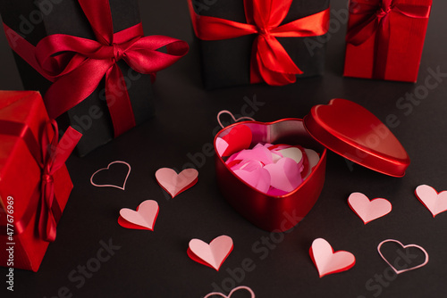paper cut hearts near metallic box and wrapped presents on black. © LIGHTFIELD STUDIOS