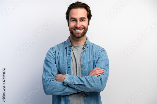 Happy man wearing basic clothes smiling at camera with hands crossed isolated over white background