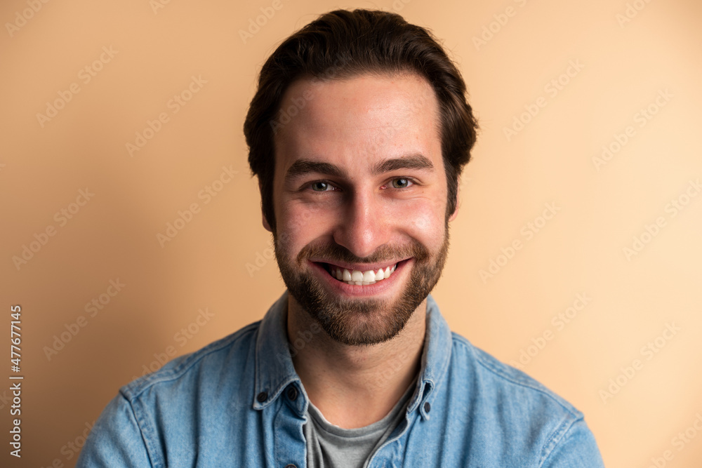 Portrait of man in blue jeans shirt isolated against orange background Portrait of man in blue jeans shirt isolated against orange background