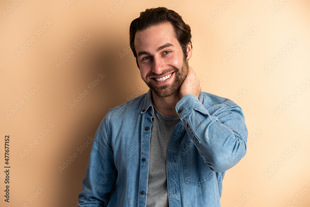 Happy smiley bearded man with dark hair holding his hand at his neck while posing Happy smiley bearded man with dark hair holding his hand at his neck while posing