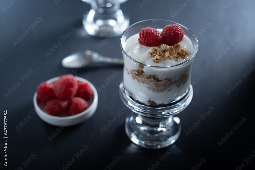 Two glass bowls of vanilla yogurt with cinnamon roll granola and raspberry topping Two glass bowls of vanilla yogurt with cinnamon roll granola and raspberry topping