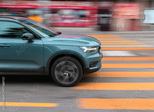 The car drives quickly through a pedestrian crossing  the background contains motion blur