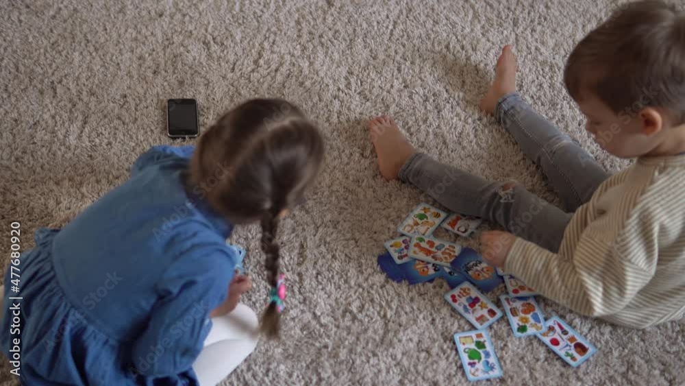 Childhood, education, hobby, family, friends, friendship concept. Happy young mother mum babysitter with little preschool kids children spend time playing card game on floor at home by fireplace Childhood, education, hobby, family, friends, friendship concept. Happy young mother mum babysitter with little preschool kids children spend time playing card game on floor at home by fireplace