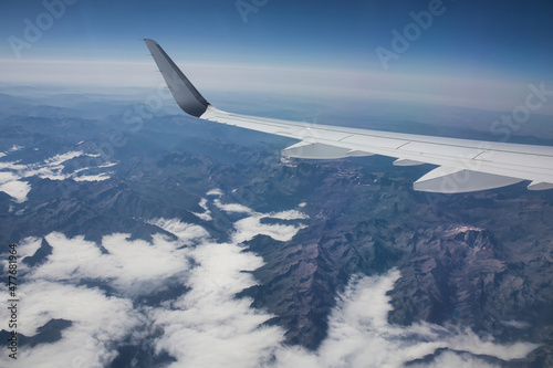 airplane wing above mountains and clouds