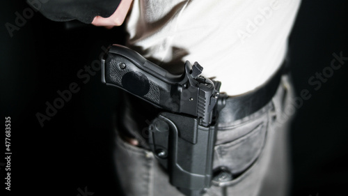 Man moving jacket to reveal a holstered firearm. Open carry and second amendment concept