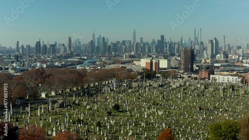 Forwards fly above historic Calvary Cemetery with tall modern high rise buildings in background. Queens, New York City, USA photo