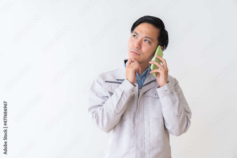 ビジネスマン　作業服　電話　考える