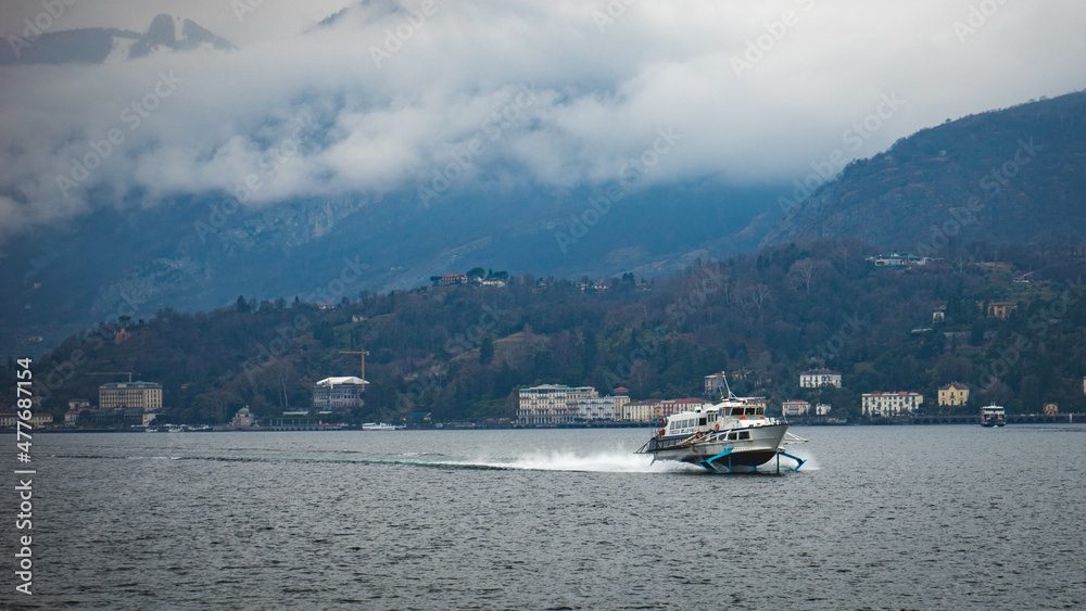 Hydrofoil boat sailing across lake Como in Italy on a cloudy winter day.