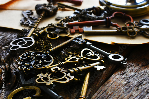A low angle image of several small vintage keys with a gold colored pocket watch. 