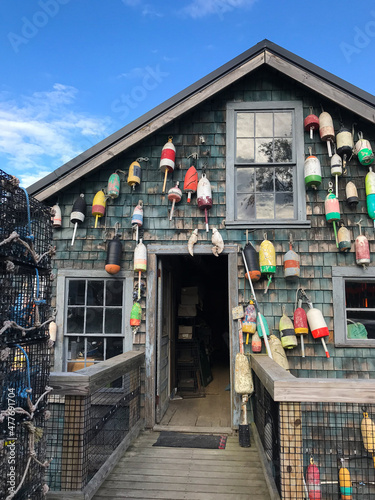 Vertical image of a wooden lobster shack covered in buoys and surrounded by lobster traps in a fishing village on Mt Desert Island, Maine, USA in summer