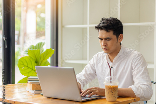 Young Asian man working on a laptop with tiger skin and a cup of coffee next to the concept of learning to work in a coffee shop.