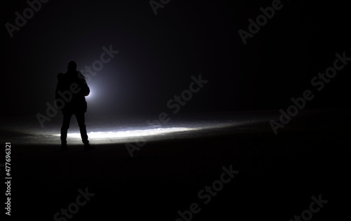 man with flashlight in winter night