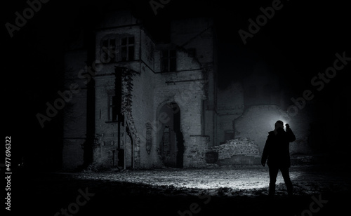a man with a flashlight near the ruins of an old castle
