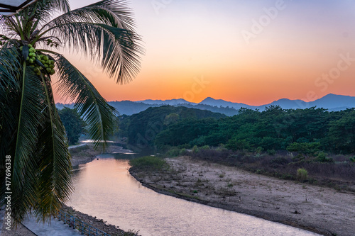 Sunset over the mountains with river and palm tree