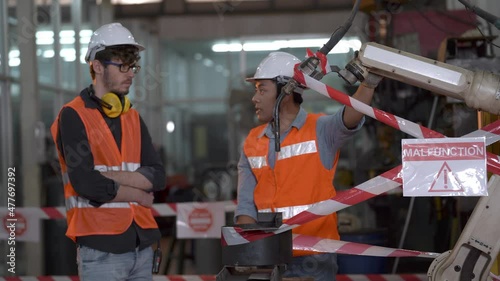  young worker labor men talking and checking robot out of order. a malfunction machine with red white line danger signage.
