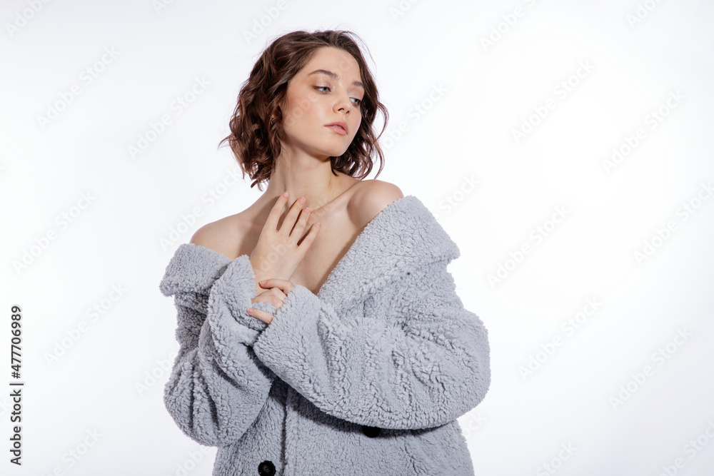High fashion photo of a beautiful elegant young woman in a pretty pale blue fur coat, suede boots posing over white background. Make up, hairstyle. Slim figure. High fashion photo of a beautiful elegant young woman in a pretty pale blue fur coat, suede boots posing over white background. Make up, hairstyle. Slim figure.