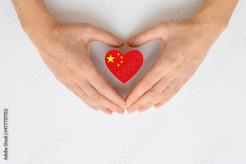 The national flag of China in female hands. The concept of patriotism, respect and solidarity with the citizens of China.