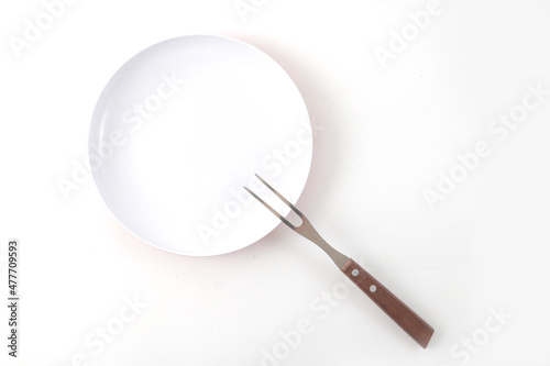 A white plate and stainless steel fork  usually used for eating steak