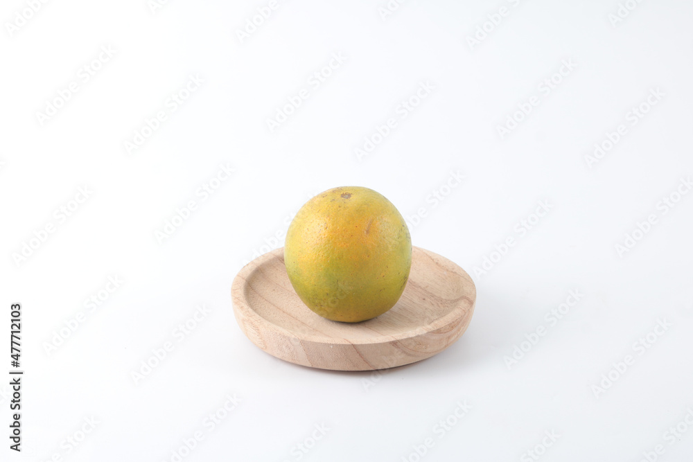 A half-riped green orange on a small wooden plate. A half-riped green orange on a small wooden plate.