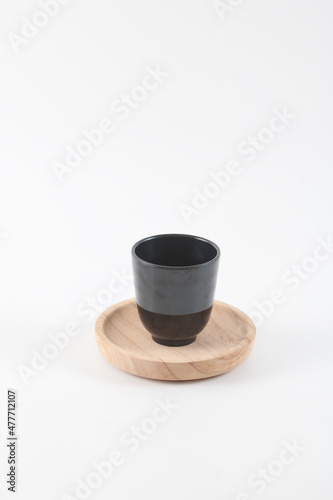 A plastic cup on a wooden tray.