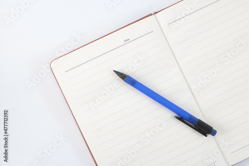A note book with a blue mechanical pencil on a flat-white background.