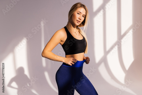 Young fit woman in sport clothes standing at gym