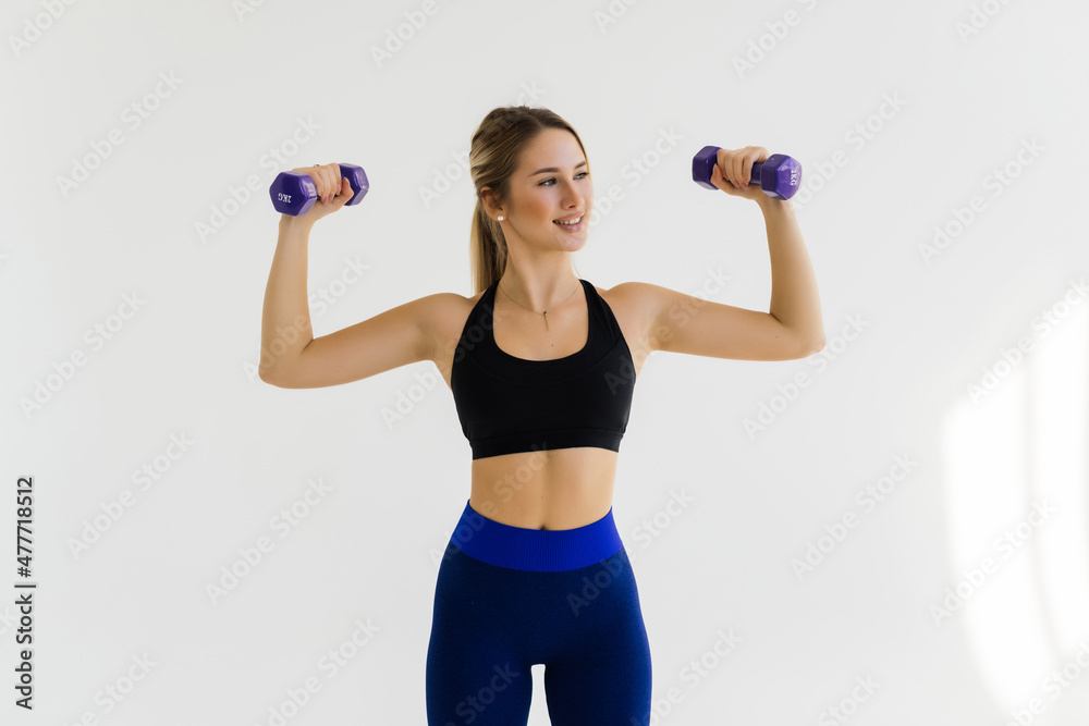 Beautiful and sporty young woman lifting up weights against white background. Beautiful and sporty young woman lifting up weights against white background.