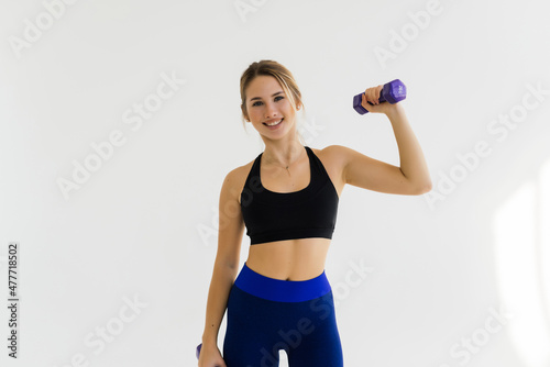 Muscular woman doing exercises with dumbbells at biceps isolated on white background. Strength and motivation.