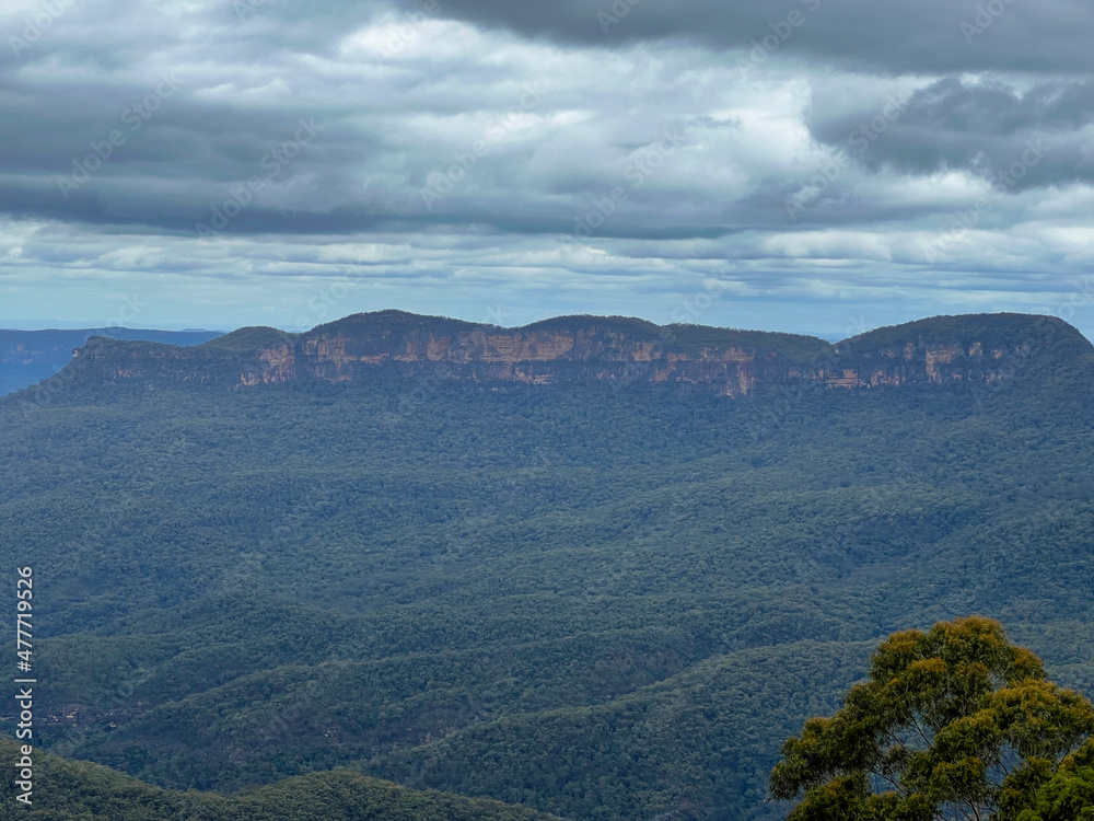 Blue Mountains with view of dark clouds covering the rainforest trees, Sydney Australia.