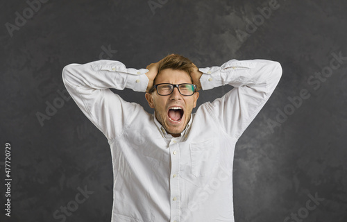 Fotografie Furious young man on black studio background scream yell with bad unexpected news