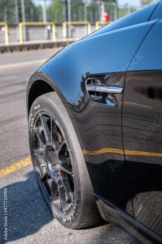 Detail on the wheel and tire of a black sports car parked on an asphalt road. © Jan