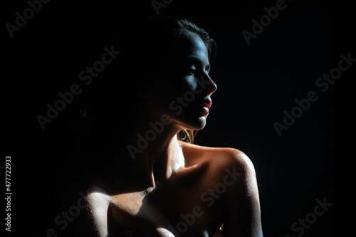 Tender girl, tenderness. Elegant young woman posing over black background. Light and shadow. Portrait of a beauty woman face.