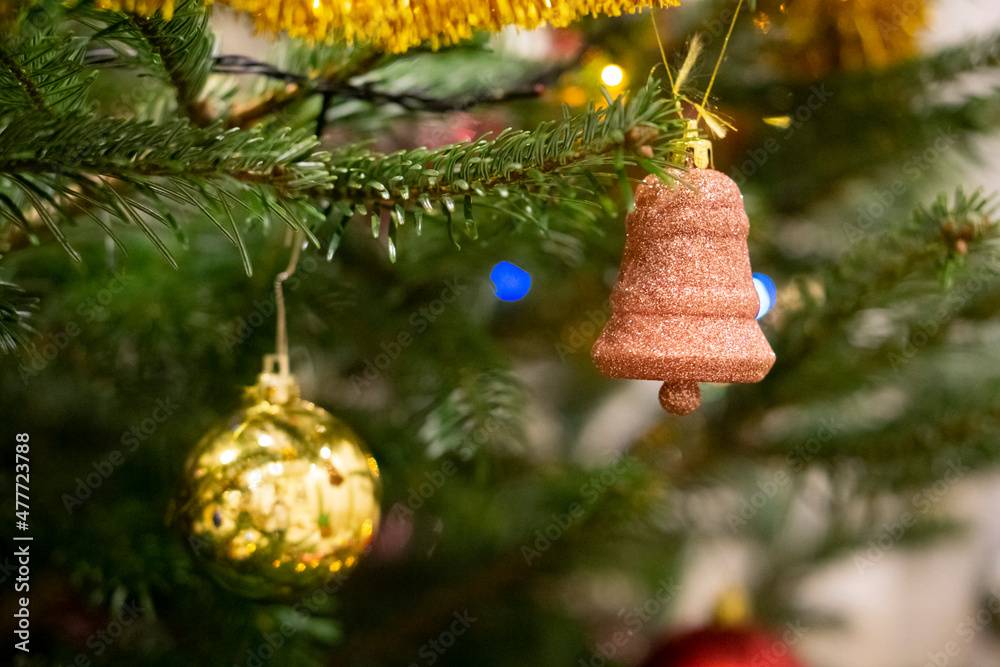 Fototapeta premium Closeup of Festively Decorated Christmas tree with beautiful toys on blurred fir fairy background. Defocused garland lights, Bokeh effect. Christmas background - baubles and branch of spruce tree.