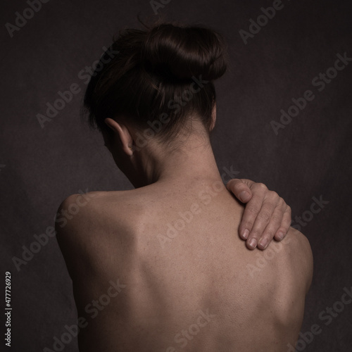 Fine art studio portrait of back of lonely naked woman with hand  photo