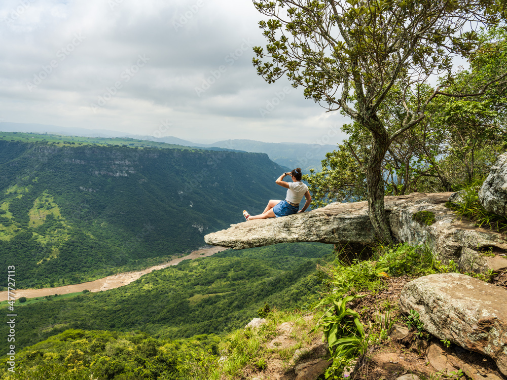 A female sitting on The Overhanging leopard rock enjoying the Oribi gorge view in Port Shepstone
