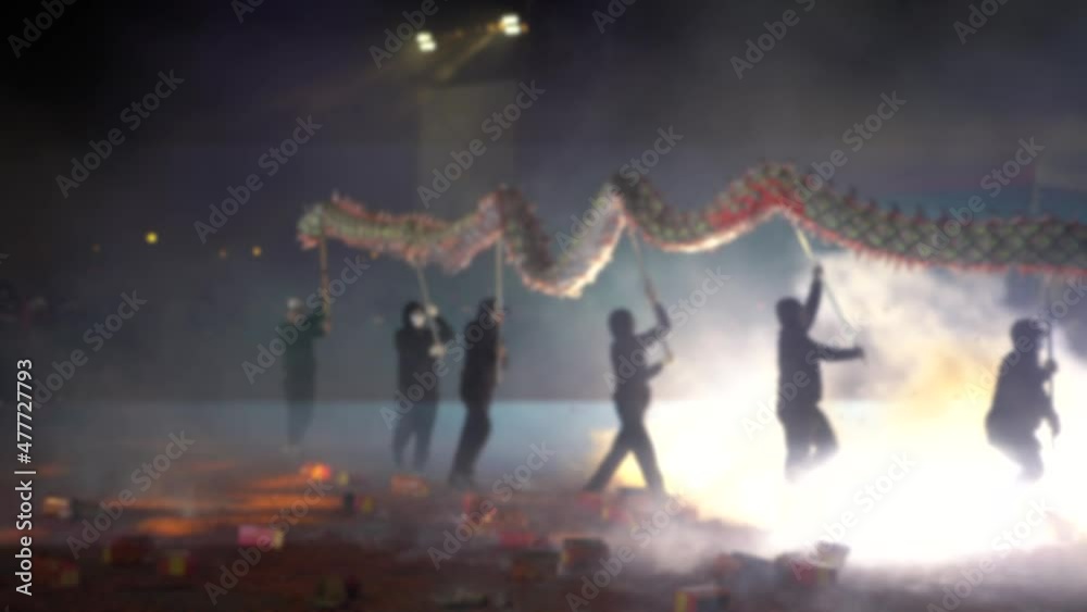 Defocused shot of festival Taiwan of Hakka Dragon Bombing Dance. Several people move dragon up and down. Spectators throw fireworks and firecrackers at dancing dragon. Blurred background on scene