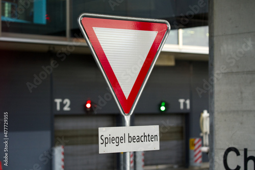 Traffic sign with text Spiegel beachten (German, translation is check mirror) at Dock Midfield at Zürich Airport on a rainy winter day. Photo taken December 26th, 2021, Zurich, Switzerland. photo