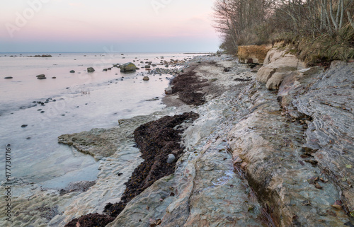 Scenic view to the coastal  limestone terrace cliff formations with the sunset colored sea and sky background photo